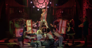 Craig Urbani as Frank-N-Furter with arms raised, surrounded by the cast of The Rocky Horror Show on stage at Montecasino Theatre