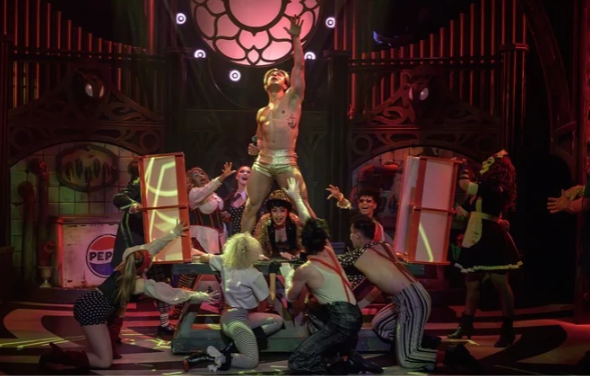 Craig Urbani as Frank-N-Furter with arms raised, surrounded by the cast of The Rocky Horror Show on stage at Montecasino Theatre